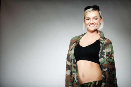 woman in military clothes with sunglasses army girl on gray background.の写真素材