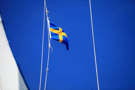 Swedish flag on ship with blue sky on backgroundの写真素材