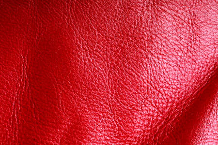 Red leather texture background closeup. Folds wavy natural skin materialの写真素材