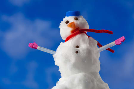 Little happy christmas snowman in blue screw top as hat red scarf and pink gloves outdoor  Winter season seasonal specific  Blue sky background  の写真素材