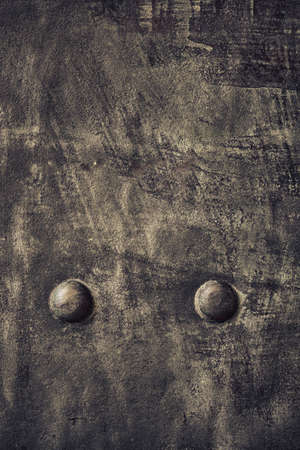 Closeup of grunge black metal plate with rivets and screws as background or textureの写真素材