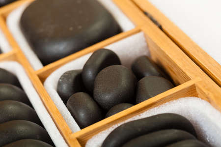 Beauty salon. Close up of black spa zen massage stones in wooden case with white blank copy space for text message. Relax concept.の写真素材