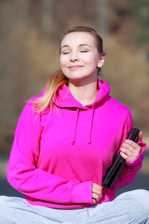 Fitness young woman sport teenage girl with close eyes in pink tracksuit holding tablet touchpad computer getting some sun on her face outdoor. Spring.の写真素材