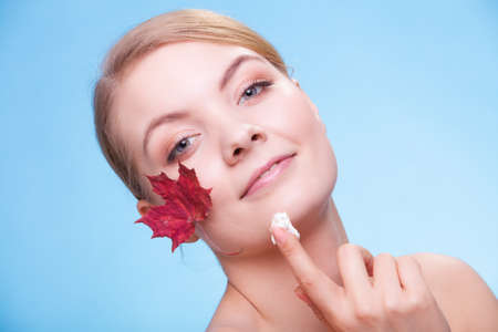 Skincare habits. Face of young woman with leaf as symbol of red capillary skin on blue. Girl taking...