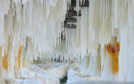 Winter scenery. Close up detail of old pier in Gdynia Orlowo Poland with ice formations icicles. Frozen Sea Baltic covered with snow, seasonal specific.の写真素材
