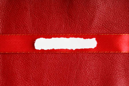 Piece scrap of white torn or ripped paper banner, blank copy space for text message on red leather backgroundの写真素材