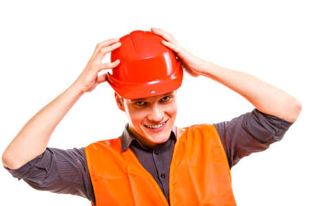 Young man construction worker builder foreman in orange safety vest and red hard hat isolated on white. Safety in industrial work. Studio shot.の写真素材
