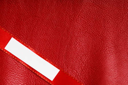 Piece scrap of white paper banner, blank copy space for text message on ribbon red leather backgroundの写真素材