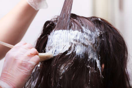Brunette woman in hairdressing beauty salon  Girl dying hair by hairstylist  hairdresser colouring client hair  の写真素材
