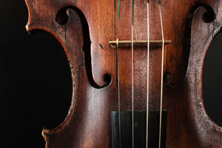Closeup of old wooden violin stringed instrument on dark gray. 