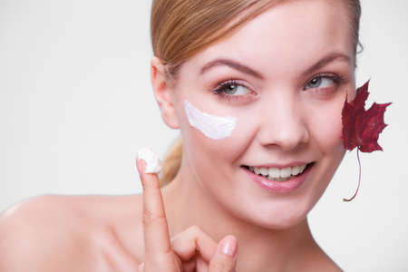  Face of young woman with leaf as symbol of red capillary skin on gray. Girl taking care of her dry...