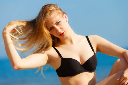 Summer vacation. Sexy girl in bikini sunbathing tanning on the beach. Young woman relaxing on the sea coast. Summertime.の写真素材