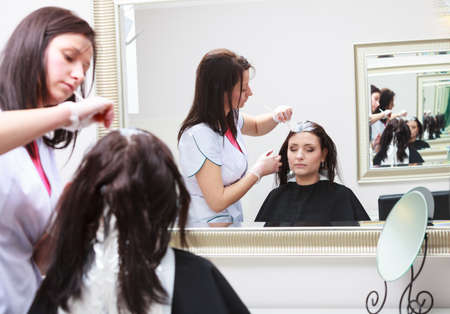 Professional female hairdresser applying color to female customer at design hair salon, woman having her hair dyed, Hair dye colouring in processの写真素材