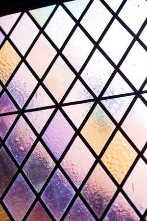 Stained glass with multi colored diamond pattern as background pink violet toneの写真素材