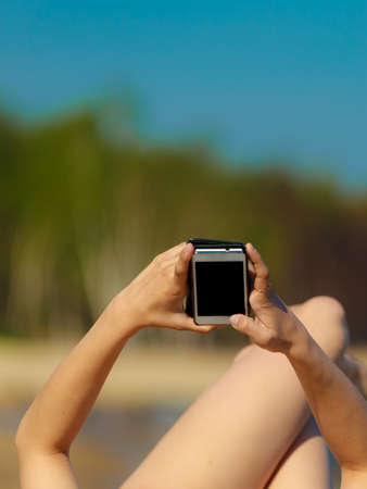 Summer vacation. Closeup of female hands. Girl sunbathing tanning on the beach. Young woman relaxing...