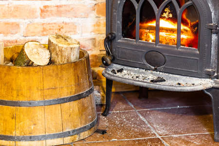 Winter at home. Closeup of fireplace with orange fire flame and firewood in the barrel interior. Heating.の写真素材