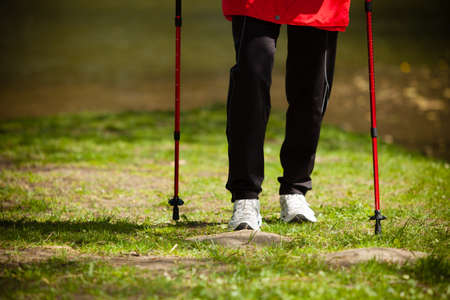 Nordic walking. Closeup of female legs hiking in the park. Active and healthy lifestyle.の写真素材