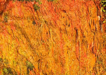 Background of natural wet orange stone wall texture rough rock surface
