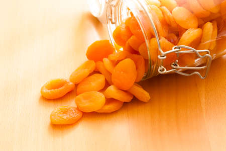 Healthy nutrition and diet. Closeup of glass jar of dried fruits apricots on wooden table. Food.の写真素材