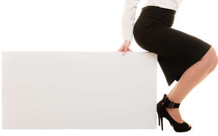 Advertisement. Closeup of female legs. Woman sitting on blank banner isolated. Businesswoman recommending product.の写真素材