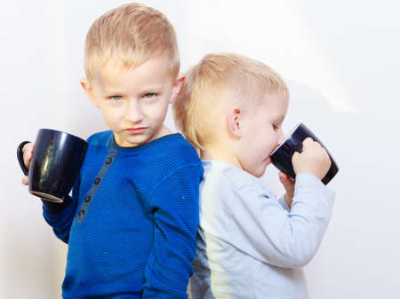 Happy childhood  Two brothers funny little boys children kids standing back to back drinking tea  Sibling rivalry の写真素材