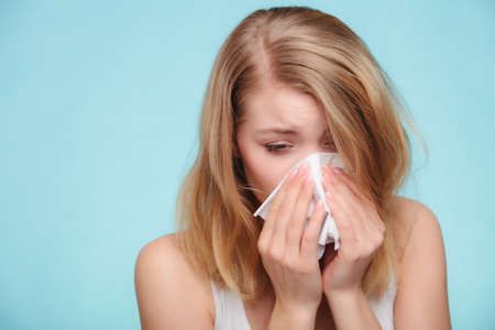 Flu cold or allergy symptom  Sick woman girl sneezing in tissue on blue  Health care 