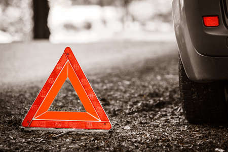Car transportation. Breakdown of car transporation. Closeup of red warning triangle sign symbol on the forest road.の写真素材