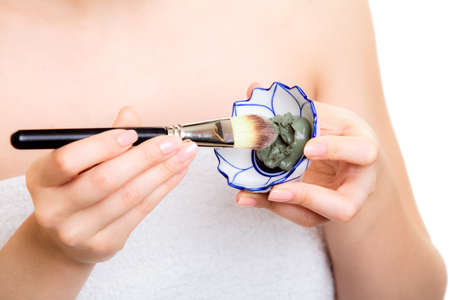 Skin care. Closeup of cosmetic. Woman with brush applying clay mask on face. Girl taking care of dry compexion. Spa.の写真素材