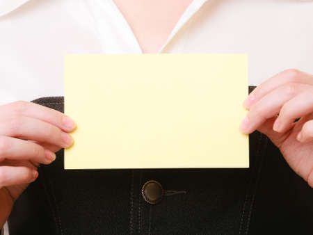 Advertisement. Blank copy space yellow business card in hands of woman. Businesswoman recommending your productの写真素材