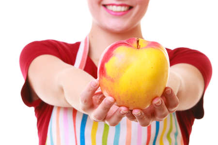 Happy housewife or chef in colorful kitchen showing red yellow apple healthy fruit isolated studio...