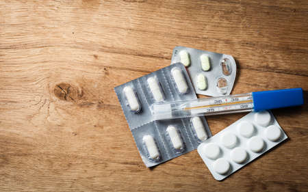 Medical. Packages of pills tablets drugs and mercury thermometer on wooden background. Pharmacy.