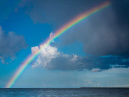 landscape view on cloudy sky with colorful rainbow at sea or ocean outdoor. Weather.の写真素材