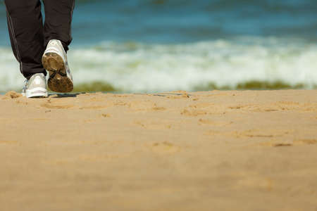 Jogging and walking. Closeup of female legs hiking on the beach. Active and healthy lifestyle.の写真素材