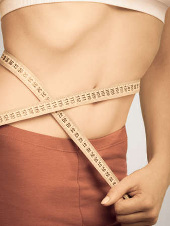 Weight loss, healthy lifestyle concept. Measuring tape on woman body, fit girl measuring her waistlineの写真素材