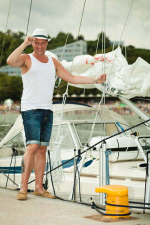 Travel tourism vacation and people concept. Fashion portrait of handsome man on pier against yachts in portの写真素材