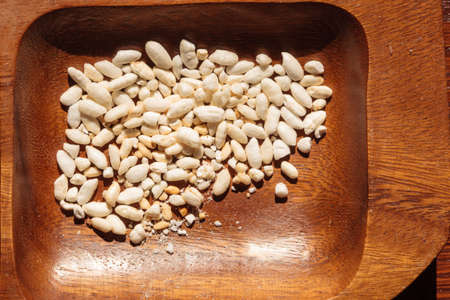 Snacks. Closeup of puffed roasted rice in brown wooden bowl. Unhealthy food.の写真素材