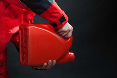 Closeup of male hands with petrol canister. Man industrial worker of gas station wearing red...