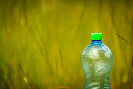 Water bottle on green grass nature background with copy space. Summer and thirstの写真素材