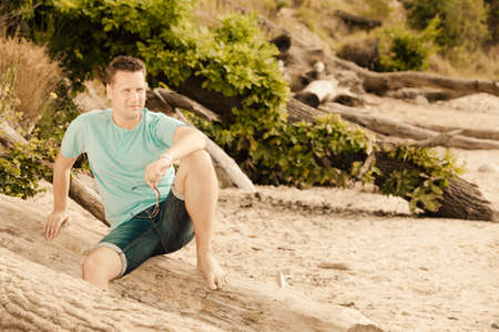Happiness summer vacation and people concept. Fashion portrait handsome man on the beach, guy sitting on treeの写真素材