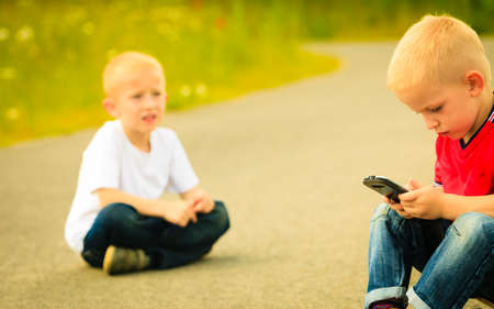 Little boy child kid  playing games on smartphone mobile phone outdoor. Technology generation.