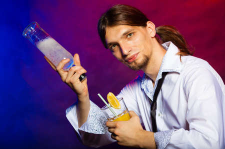 Young stylish man bartender with bottle alcohol pouring a drink