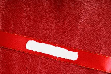 Piece scrap of white torn or ripped paper banner, blank copy space for text message on red leather backgroundの写真素材