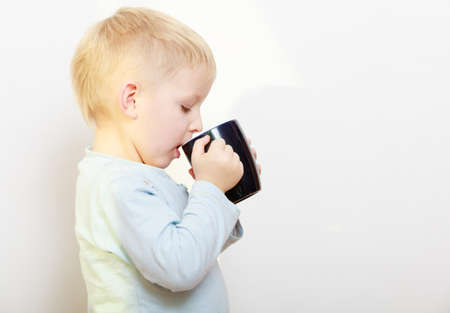 Happy childhood. Funny little boy child kid drinking tea. Indoorの写真素材