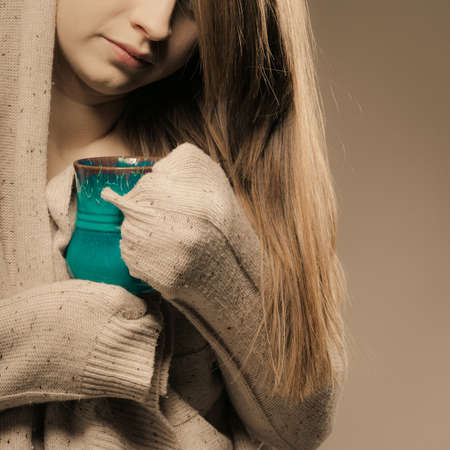 Hot beverage. Closeup of girl drinking cup mug of drink tea or coffee. Woman warming herselfの写真素材