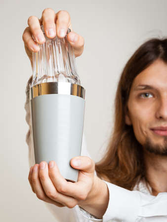 Young stylish man bartender with shaker making alcohol cocktail drink studio shot on grayの写真素材