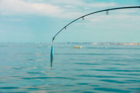 Sport and recreation. Fishing bait - rod with wobbler against the blue sea water surfaceの写真素材