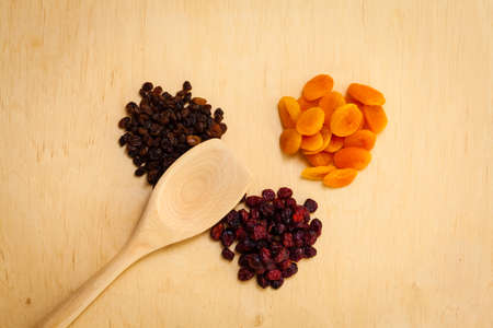 Healthy food organic nutrition. Dried dehydrated fruits raisins apricots and cranberries on wooden tableの写真素材