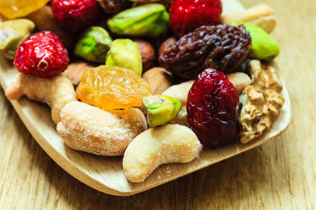 Healthy food organic nutrition. Closeup different varieties mix of dried fruits and nuts on wooden...