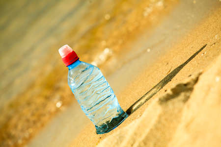thirst and bevarage. closeup of plastic bottle of water drink on a sandy summer beach. vacation fitnessの写真素材