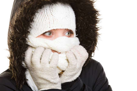 Winter vacation. Girl in warm clothes. Young woman covering her face with scarf hood from cold isolated on white.の写真素材